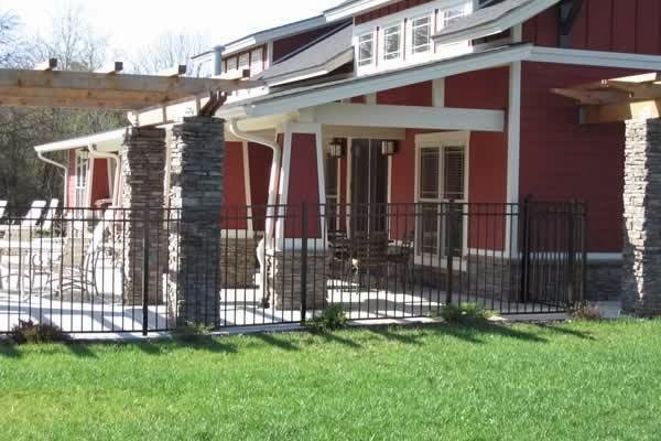 Black ornamental fence panels between stacked stone columns at a commercial building