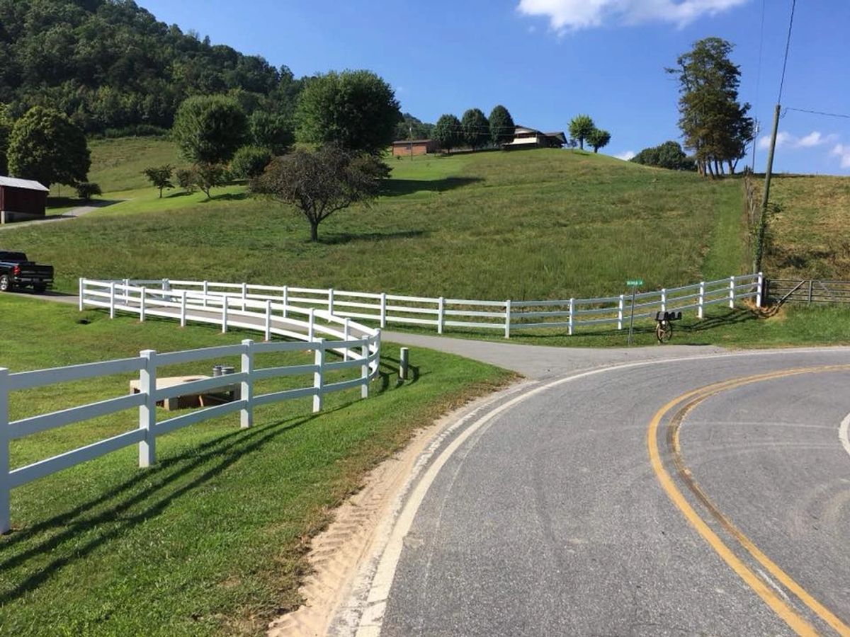 White vinyl three-rail ranch fence along a road