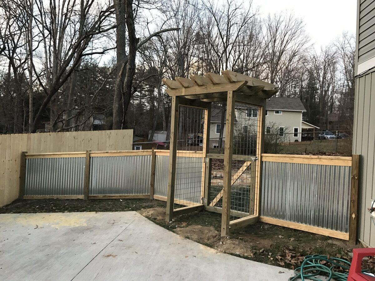 Corrugated metal panels set in a pressure-treated wood frame with a matching arbor entry