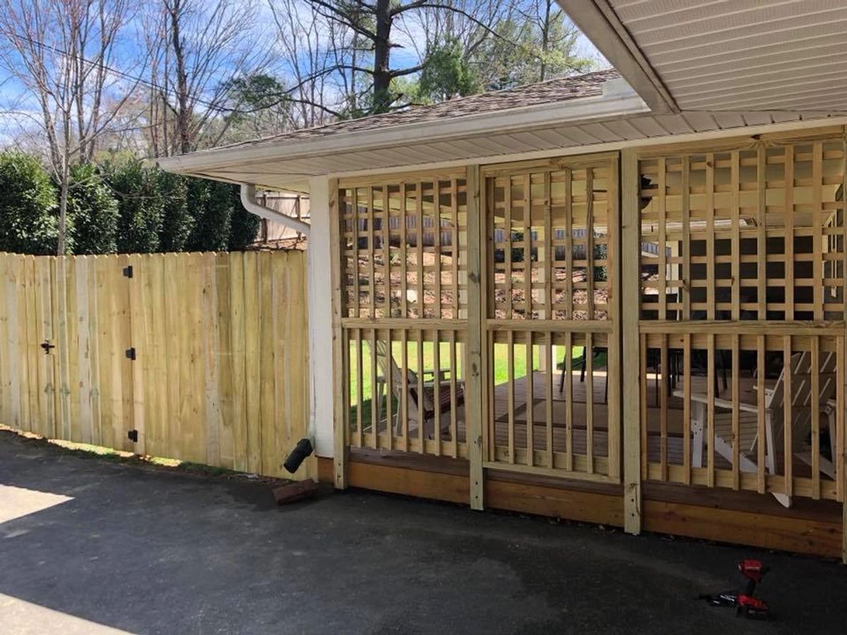 Dog-eared wood privacy fence beside a lattice porch enclosure