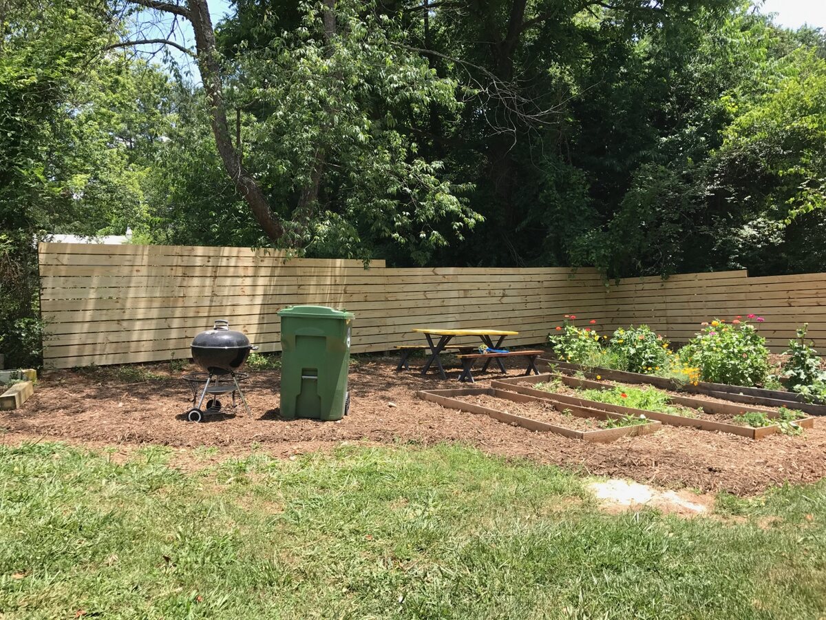 Horizontal-board wood privacy fence enclosing a backyard with raised garden beds