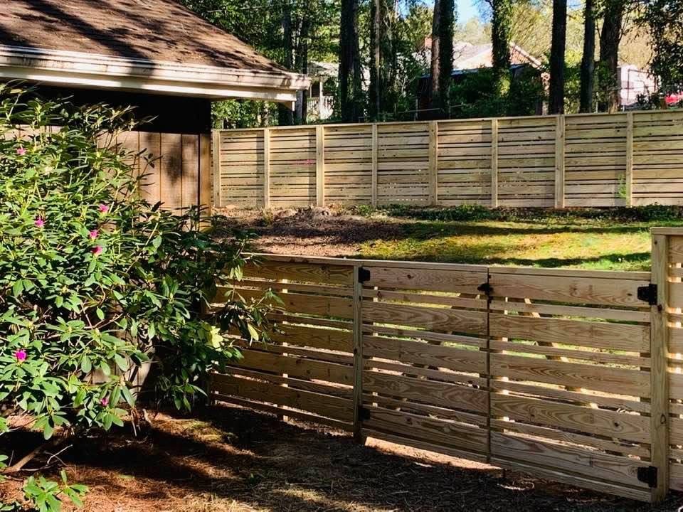 Horizontal slat wood privacy fence with a matching double gate beside a garden bed